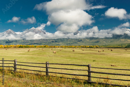 Amazing mountain landscape with cloudy sky, lath fence in the foreground and haystacks, Siberia, Irkutsk region, Russia
