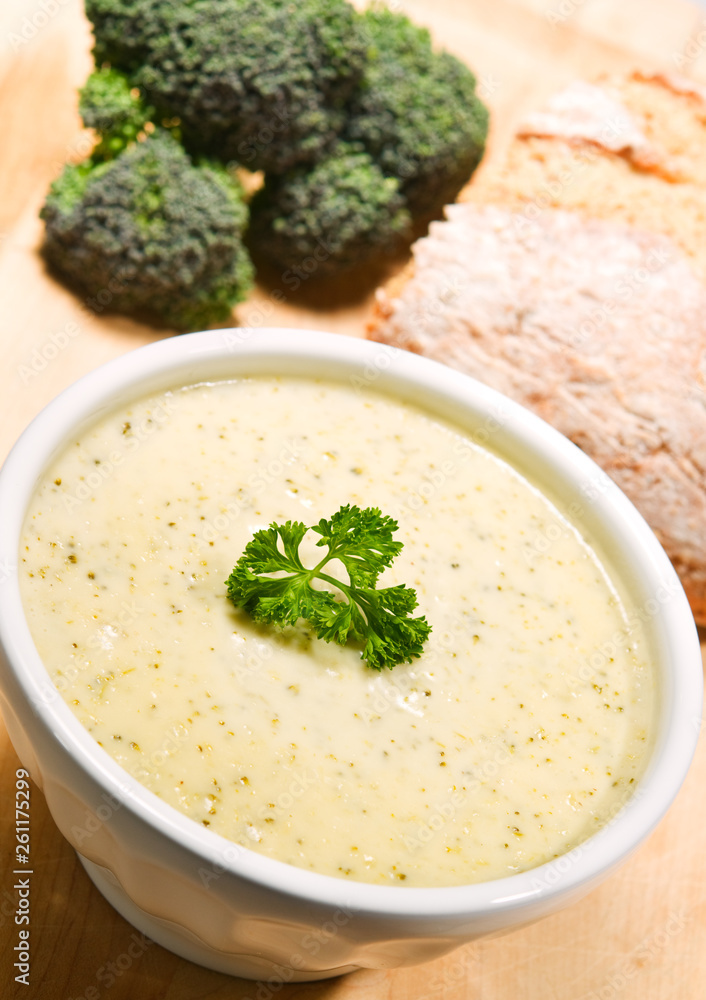 Brocolli cheddar soup in a white bowl next to a loaf of bread. Brocolli cheddar soup in a white bowl next to a loaf of bread.