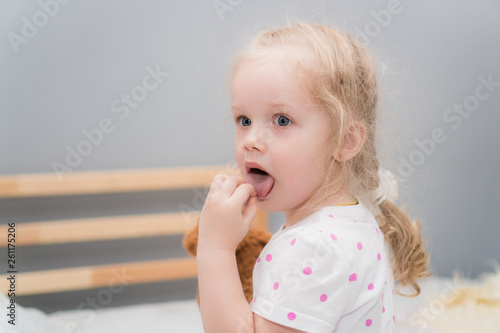 Little girl shows tongue and looks away