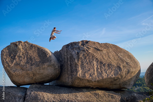 Adventurous teenage boy  jumping from one large boulder to another one. photo