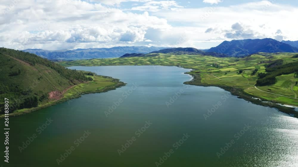 Aerial view of Peruvian landscape with green agricultural fields and Puray a big lake with blue water near Cusco in the Andes range of Peru. Clouds with blue sky. Aerial view of Peruvian landscape with green agricultural fields and Puray a big lake with blue water near Cusco in the Andes range of Peru. Clouds with blue sky.