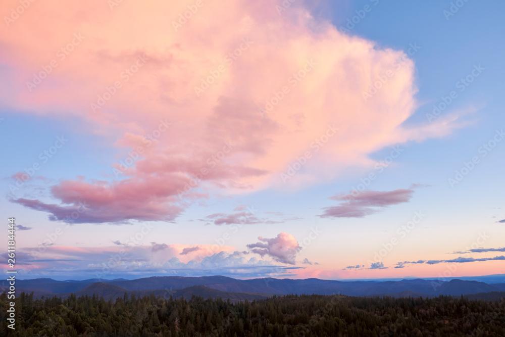 Pink sunset clouds moving over a forest wilderness area in the Sierra Nevada Mountains of Northern California. 