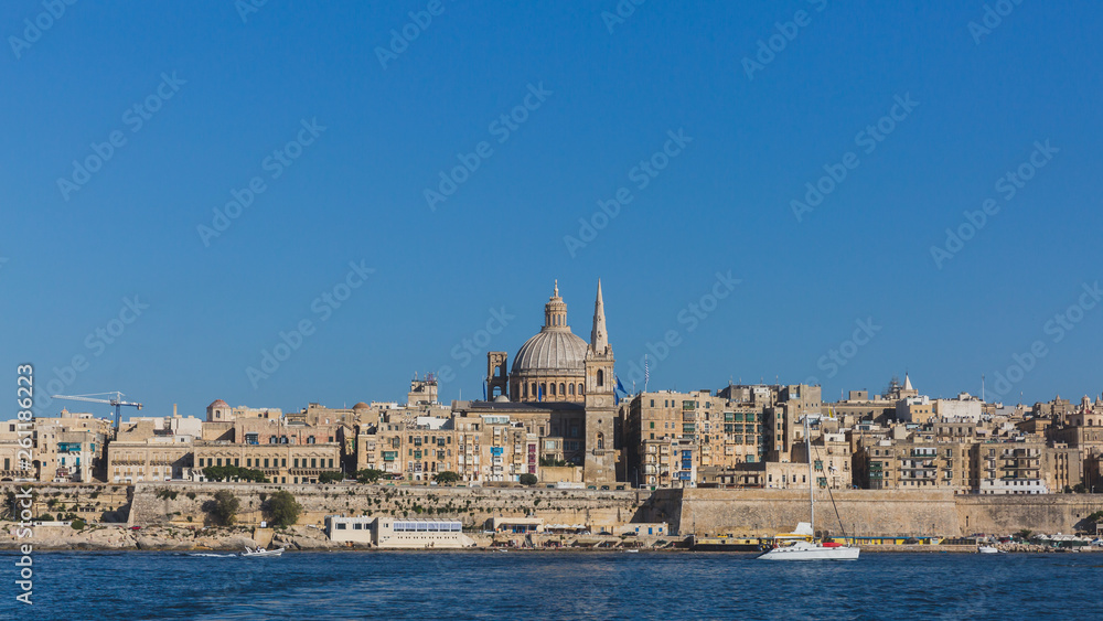 Skyline of Valletta, Malta under blue sky, with dome of Basilica of Our Lady of Mount Carmel and tower of St Paul's Pro-Cathedral