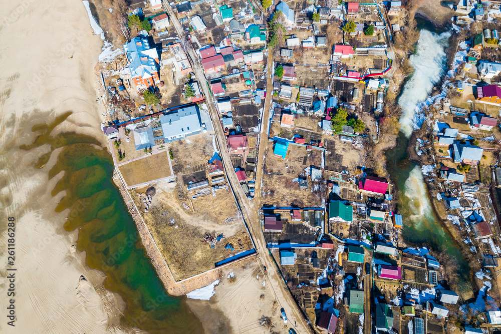 Obraz premium Aerial photography of a small village with villas and cottages, river, beach,forest and roads. Helicopter drone shot