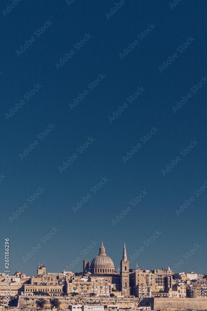 Skyline of Valletta, Malta under blue sky, with dome of Basilica of Our Lady of Mount Carmel and tower of St Paul's Pro-Cathedral