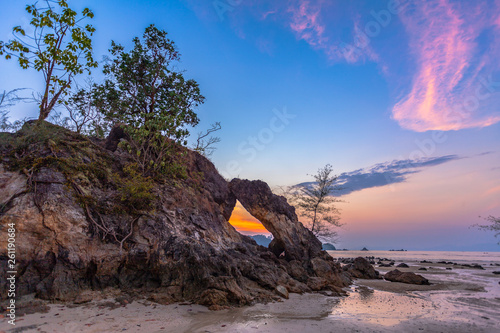 beautiful sunset in the hole of unusual rock wave eroded into the cavity like the arch with a hole in the middle peaceful atmosphere at Hin Thalu Buffalo beach on Phayam island Ranong Thailand.. photo