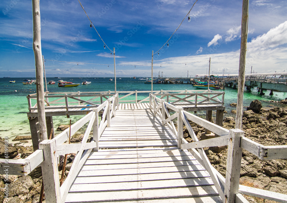 The white wooden bridge, the destination is a beautiful sea with blue sky.