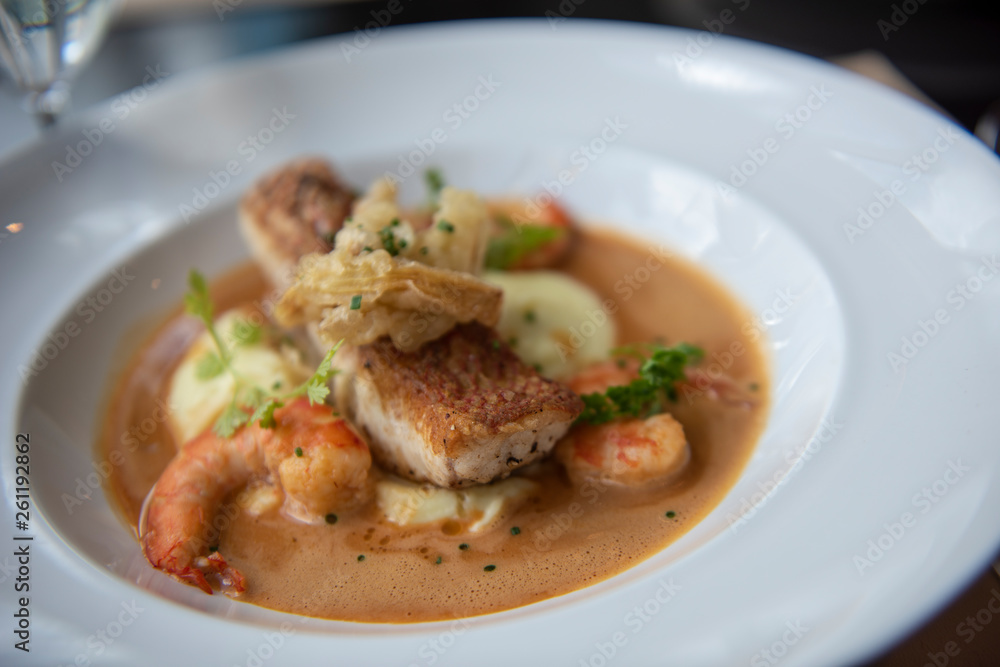 Fresh sea food menu with red snapper, shrimp, potato and topped with brown gravy. Served on a round white plate as a main course in a modern French restaurant in Bangkok, Thailand. Fresh sea food menu with red snapper, shrimp, potato and topped with brown gravy. Served on a round white plate as a main course in a modern French restaurant in Bangkok, Thailand.