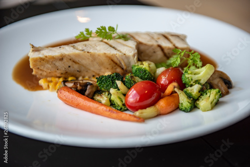 A grilled chicken served with broccoli, red tomato, carrot, mushroom and corn in Asian style. Served as a main course in a modern French restaurant in Bangkok, Thailand.