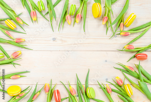 Fototapeta Naklejka Na Ścianę i Meble -  Frame made of tulip flowers with macaroons on wooden background. Top view. Floral mock up concept