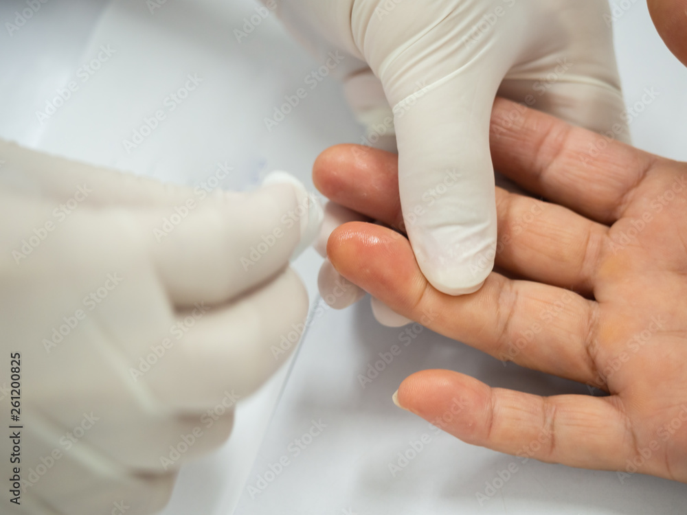 Close up of nurse hand using lancet on finger to check blood sugar level with glucose meter at laboratory.Doctor measuring a patient's blood glucose.Human blood sugar test concept Close up of nurse hand using lancet on finger to check blood sugar level with glucose meter at laboratory.Doctor measuring a patient's blood glucose.Human blood sugar test concept