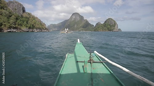 Traditional wooden boat in the asian ocean motoring along the lime stone coast of el nice, Philippines. Asian ship following an other boat in tropical blue water. Stabilized travel shot. photo