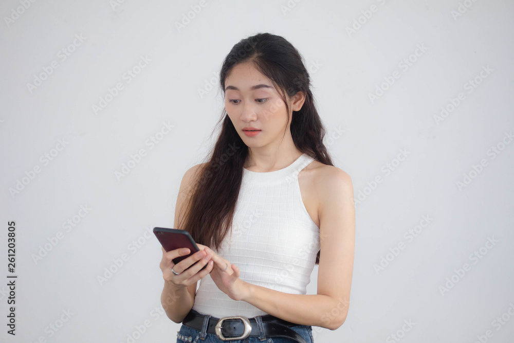 Naklejka premium Portrait of thai china adult beautiful girl White shirt blue jeans using her smart phone
