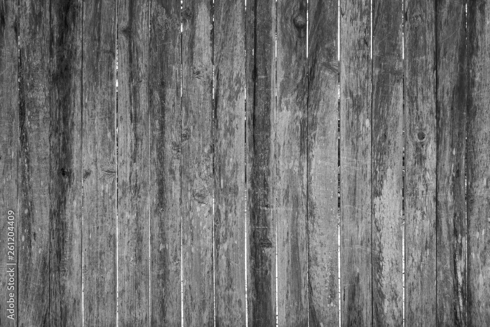 Full frame background of an old, faded and scratched wooden board wall or fence in black and white.