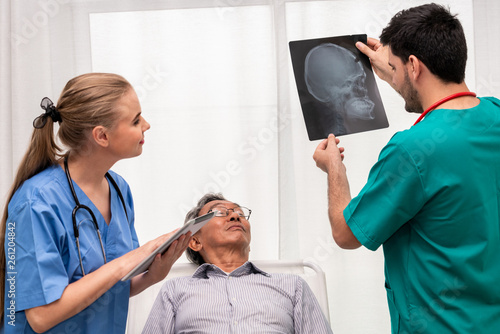 Doctor team work with x ray film image of the senior adult patient lying on the bed in the hospital ward room. Medical group teamwork and healthcare person staff service. photo