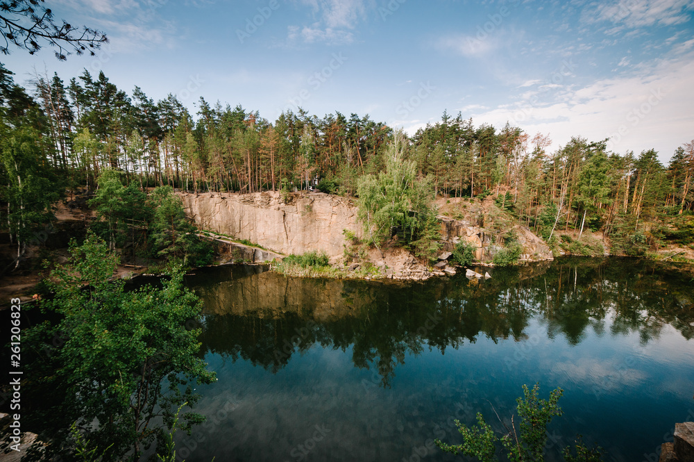 Lake on the background of rocks and fir trees. Canyon. The nature of autumn. Place for text and design. Landscape of an old flooded industrial granite quarry filled with water.