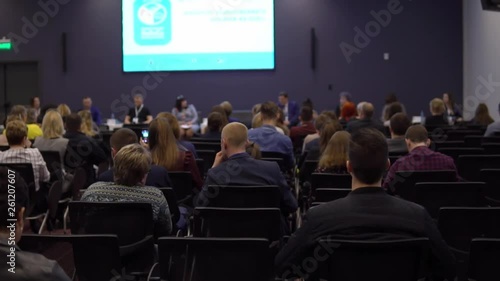 a large group of people at a business development conference are listening to business coaches