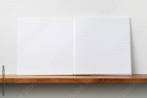white square notebook on bookshelf and white wall