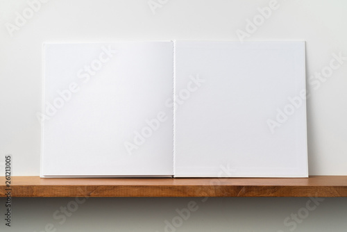 white square notebook on bookshelf and white wall