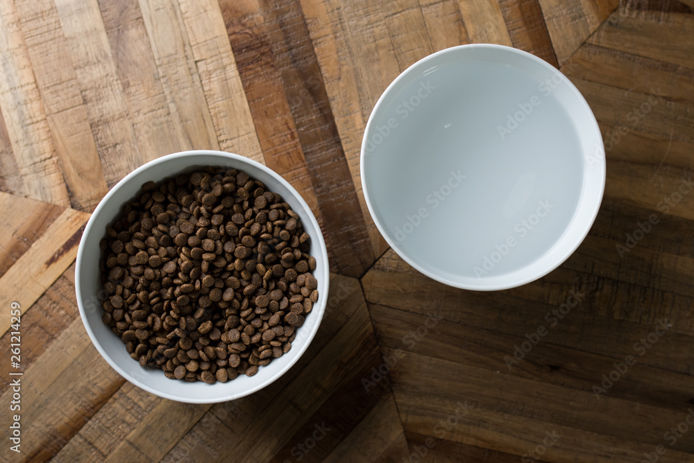 cat food dishes - top view of two bowls of dry cat food and water standing on a wooden table cat food dishes - top view of two bowls of dry cat food and water standing on a wooden table