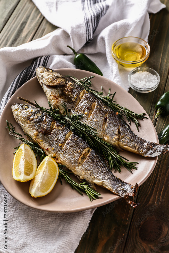 Plate with tasty cooked fish on wooden table Plate with tasty cooked fish on wooden table