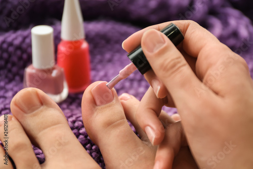 Woman doing pedicure on color background  closeup