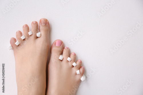 Woman with toe separators and fresh pedicure on light background