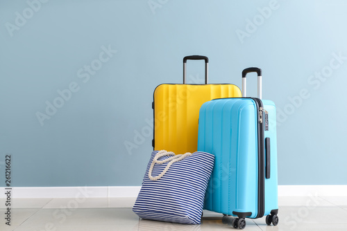 Obraz na plátně Packed suitcases and beach bag near color wall