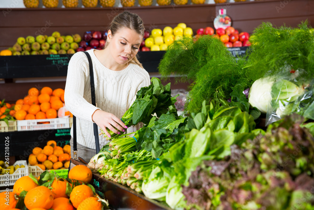 Female customer choosing greens and letuce on the supermarket