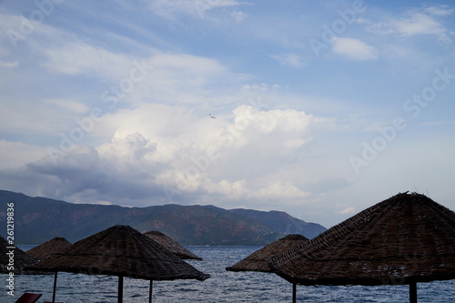 Sea  mountain and braided umbrellas in a summer day