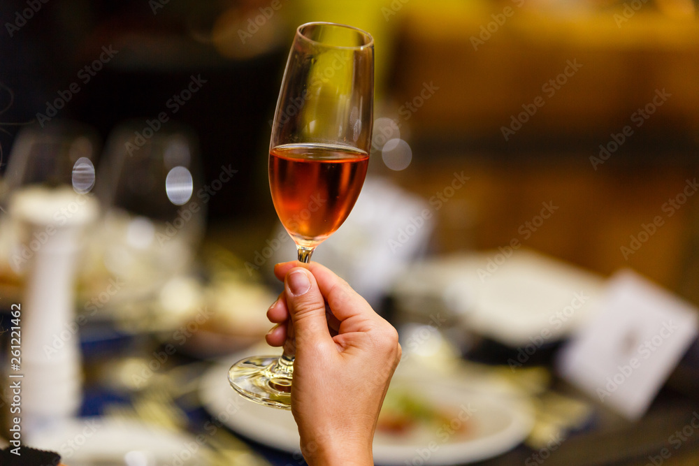 Woman in elegant pink dress drinking wine in restaurant with lights in background