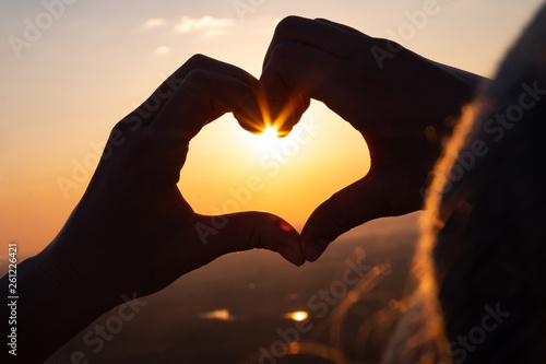 Girl in love  enjoying the sunset  makes the heart of the hands