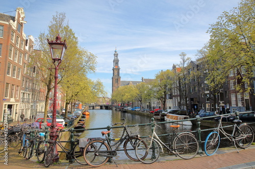 Westerkerk Church clock tower and historic buildings viewed from Reestraat Bridge (along Prinsengracht Canal) in Amsterdam, Netherlands  photo
