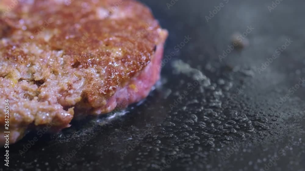Cooking a hamburger, patty or steak. On a hot stove, a cook fries meat in a professional kitchen