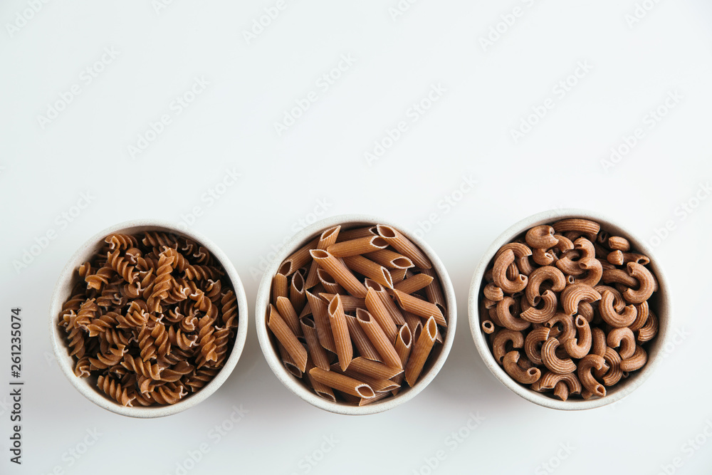 Variety of whole grain pasta, horizontal, white background, free space for text Variety of whole grain pasta, horizontal, white background, free space for text