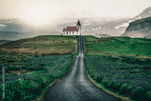 Ingjaldsholl church in Hellissandur, Iceland in the field of blooming lupine flowers with background of Snaefellsjokull mountain. Beautiful sunny scenery of summer in Iceland. photo