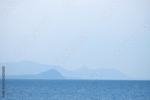 Blurred deep blue sea with water waves and mountains view for background backdrop 