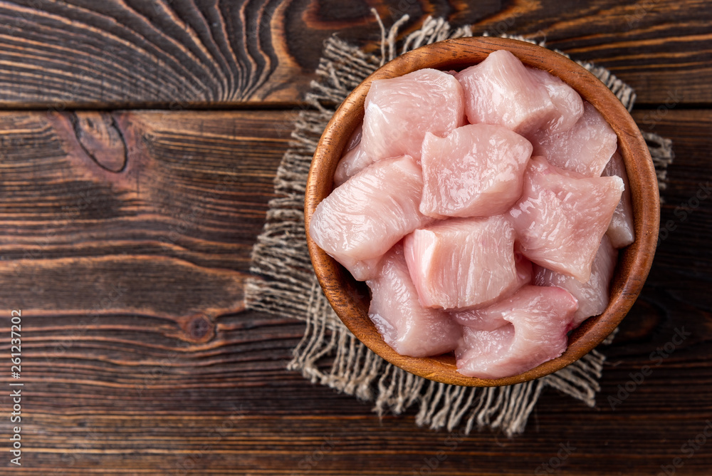 Diced raw chicken breast or fillets on dark wooden background. Diced raw chicken breast or fillets on dark wooden background.
