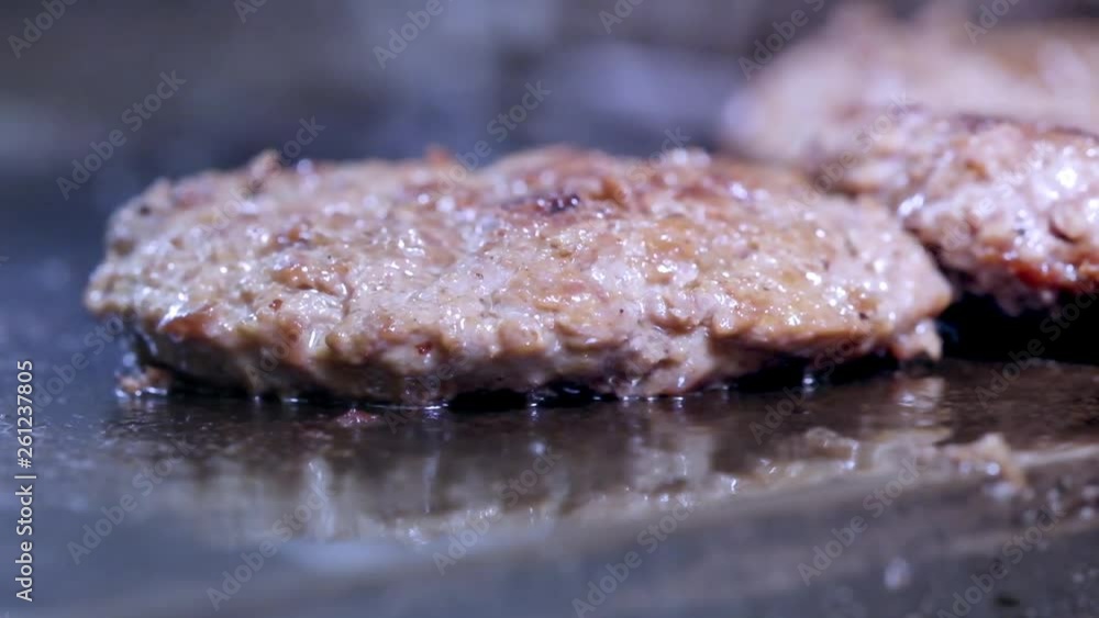 Cooking a hamburger, patty or steak. On a hot stove, a cook fries meat in a professional kitchen