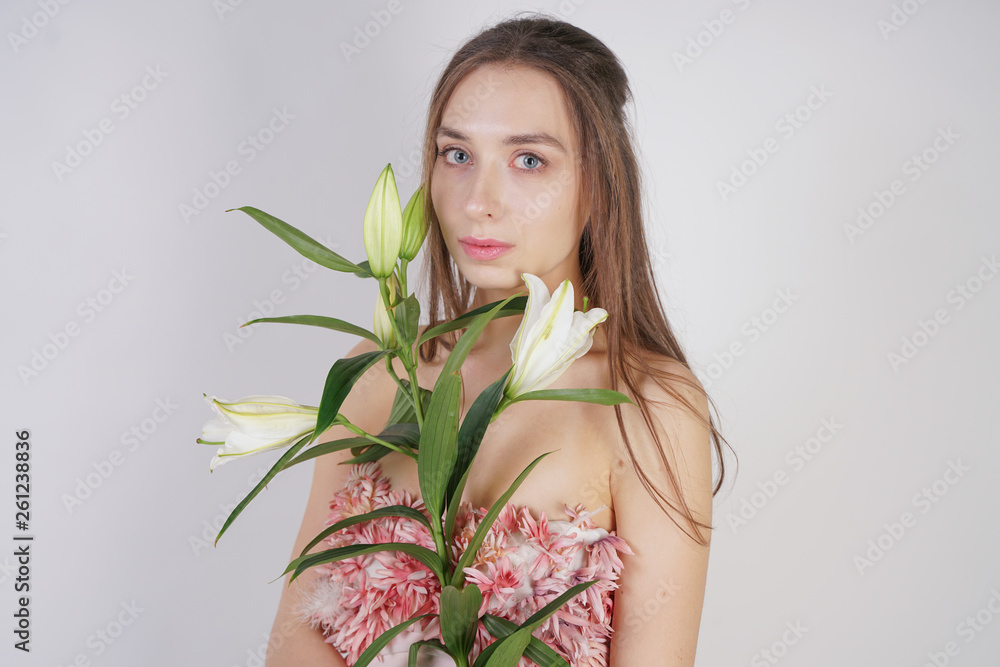 charming young caucasian girl in a pretty dress holds a lush Lily flower in her hands and stands on a white background in the Studio alone charming young caucasian girl in a pretty dress holds a lush Lily flower in her hands and stands on a white background in the Studio alone