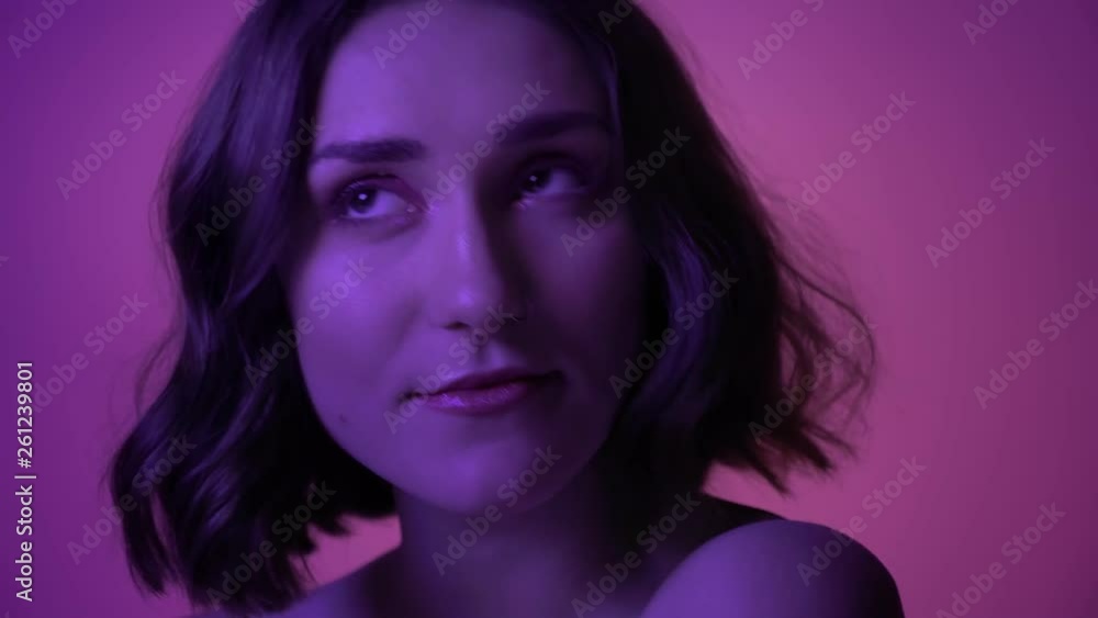 Closeup shoot of young alluring female posing seductively in in front of the camera with neon purple background Closeup shoot of young alluring female posing seductively in in front of the camera with neon purple background