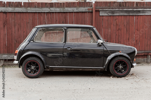 Black old classic mini cuper. Street and wooden yard. Travel photo 2019.