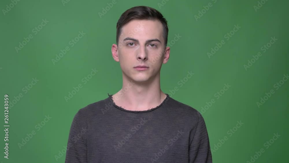 Closeup shoot of young handsome caucasian male looking straight at camera with background isolated on green Closeup shoot of young handsome caucasian male looking straight at camera with background isolated on green
