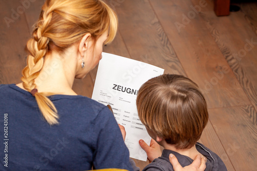 Mother comforting son despite the bad school certificate - Translation: certificate day of birth disciplines music reading religion german english mathematics art maths insufficient grade f deficient photo