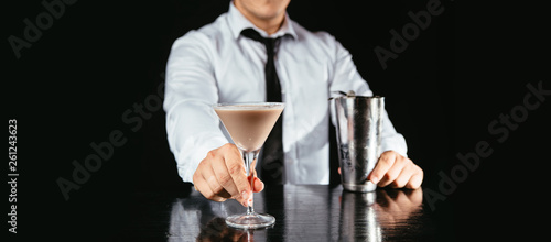 Barman makes an espresso martini. Bartender pouring creamy liqueur into a martini glass.