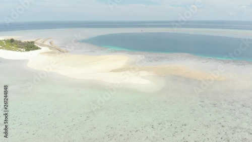 Aerial: Flying over idyllic atoll, travel destination Wakatobi National Park Indonesia Maldives Polynesia blue lagoon coral reef desert island white sand beach. Native cinelike D-log color profile photo