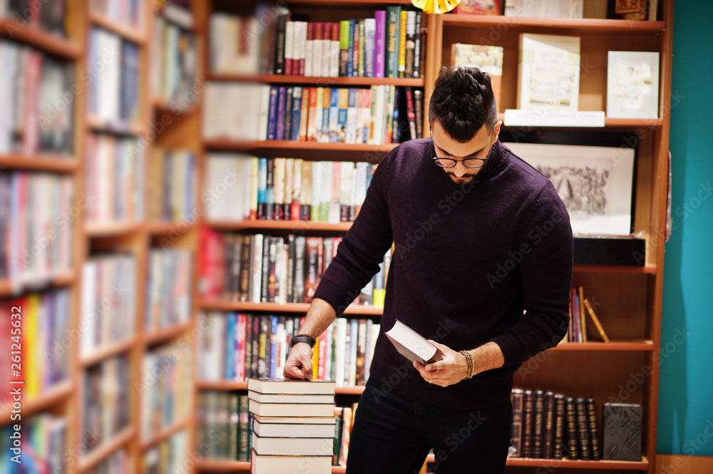 Tall smart arab student man, wear on violet turtleneck and eyeglasses, at library with stack of books. Tall smart arab student man, wear on violet turtleneck and eyeglasses, at library with stack of books.