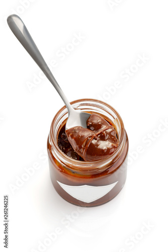 Spoon of homemade chocolate caramel sauce on jar isolated on white