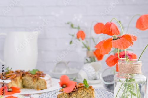 Pie with poppy seeds on a white background. Homemade pastries and red flowers.
