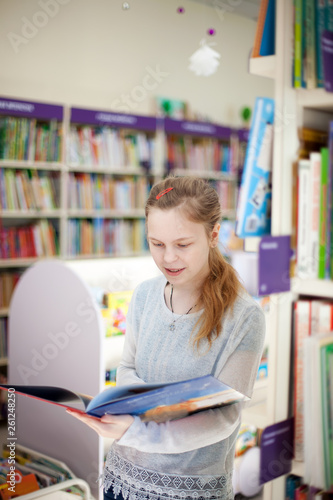  girl of 13 years old choosing book in library.